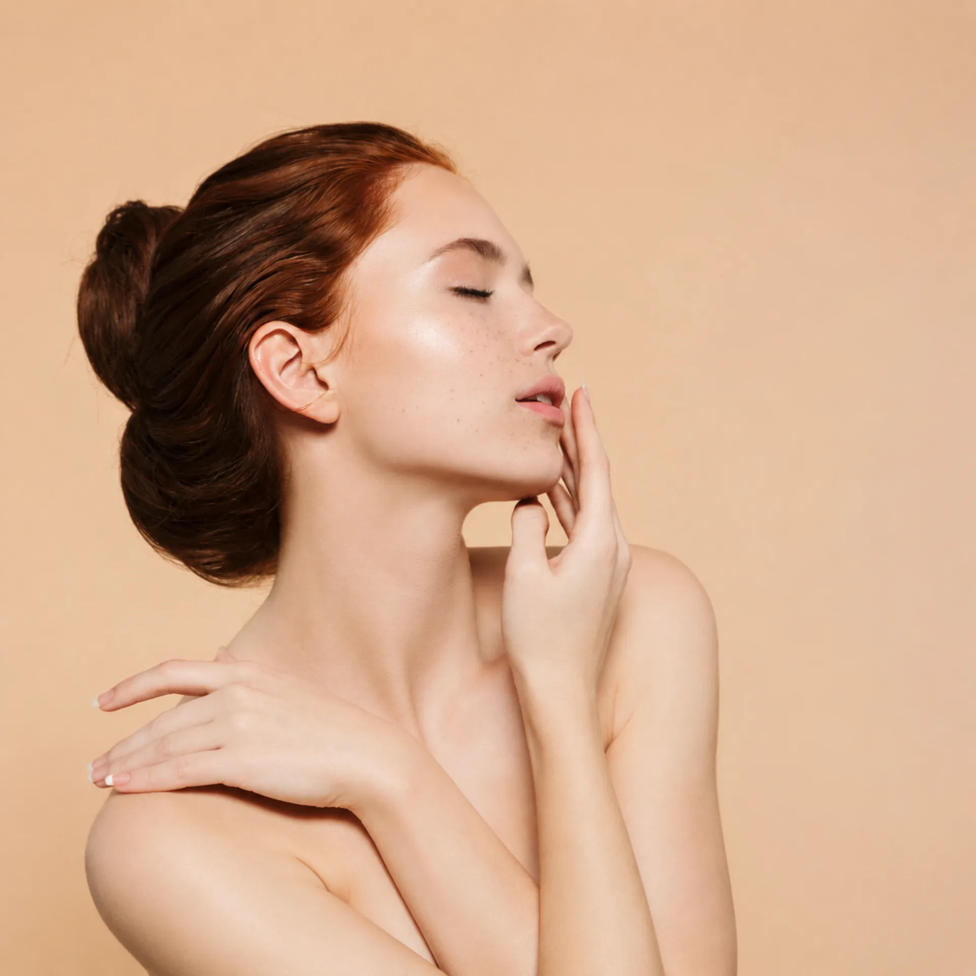 Woman with red hair against a warm peach background